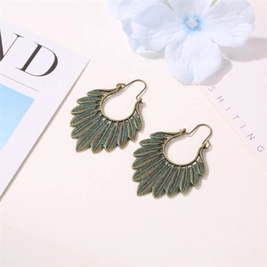 Close-up of vintage bronze leaf earrings with detailed feather texture and green patina