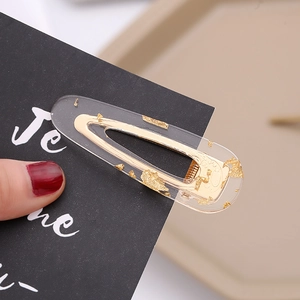 Macro detail of acetate hair clip with elegant gold leaf flakes and metal BB clip