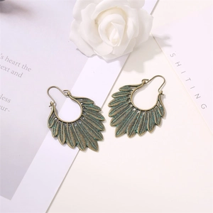 Detailed view of bronze feather earrings with intricate textures on floral background