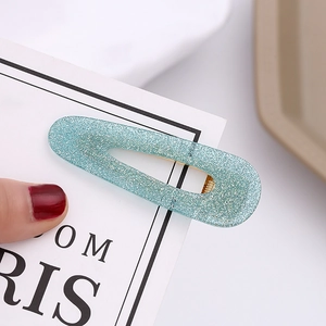 Close-up of glittery blue teardrop hair clip with silver sparkles and gold metal base