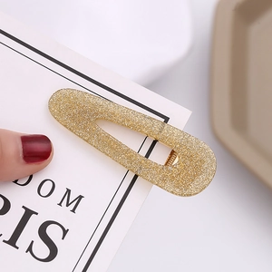 Detailed macro view of a gold glitter teardrop hair clip with a polished metal base