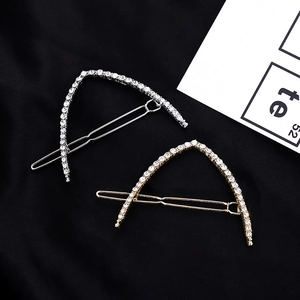 Close-up of gold and silver V-shaped hair clips with sparkling rhinestones on black background