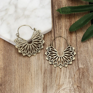 Vintage bohemian hollowed-out alloy hoop earrings in antique gold on marble surface