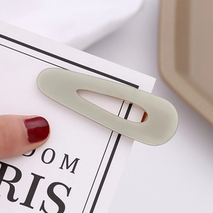 Detailed view of sage green acetate hair clip featuring a hollow water drop design