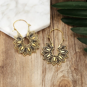 Bohemian vintage hollow mandala drop earrings with antique bronze finish on wood surface