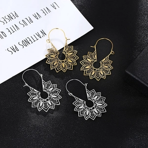 Bohemian hollow floral drop earrings set in gold and silver finish on textured background