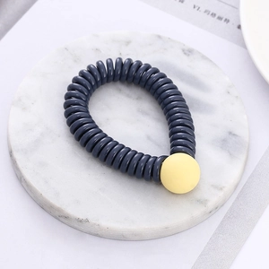 Detail of spiral hair tie with a frosted yellow bead on a marble tray background