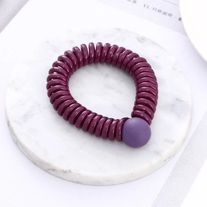Spiral elastic hair tie in deep purple with a matte round bead on marble background