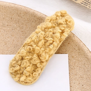 Dettaglio ravvicinato della morbida texture in lana d'agnello di un fermaglio giallo