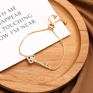Adjustable golden bolo bracelet with sparkling crystal-encrusted key pendant for women