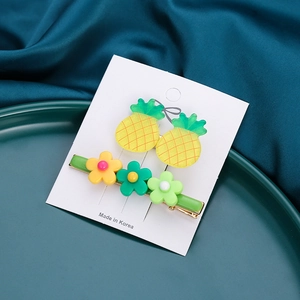 Detail of a 2-piece hair clip set featuring yellow pineapple and multi-color floral designs
