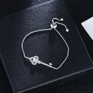 Fashion silver tone adjustable bracelet with sparkling diamond key pendant on a jewelry box