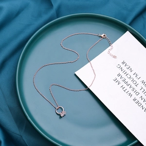Dettaglio della collana in oro rosa con ciondolo in zircone su sfondo di seta