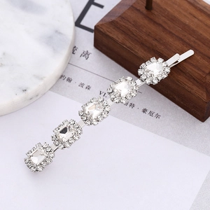 Détail d'une barrette argentée avec strass et perles sur un support en marbre