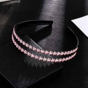 Detail view of double-layered black headband with pink rhinestone flower decorations