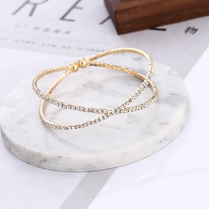 Detail of gold multi-layer crisscross open cuff bracelet with sparkling pavé rhinestones