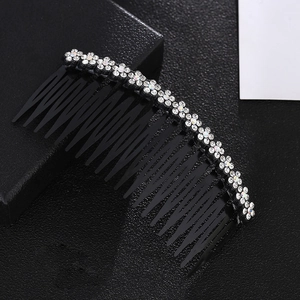 Close-up of black plastic hair comb with sparkling white rhinestone flower decorations