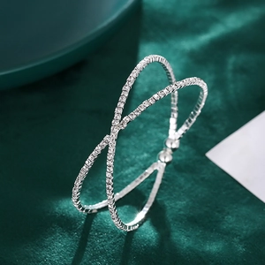 Crossed open cuff bracelet with silver plating and pavé sparkling crystals on green velvet