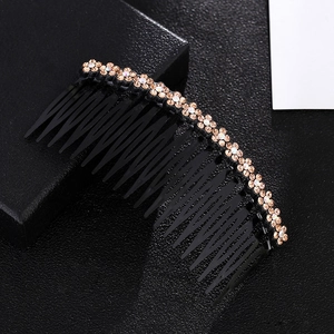Detail of amber rhinestone flower pattern on a black plastic anti-slip hair comb