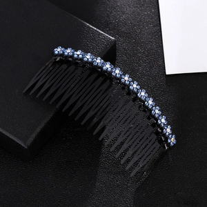 Detail shot of black wavy hair comb with blue and iridescent rhinestone floral patterns