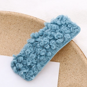 Close-up of a blue plush lamb wool rectangular hair clip showing soft curly texture