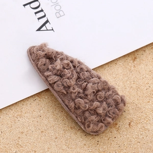 Close-up of stylish brown faux sheepskin plush hair clip with soft curly texture