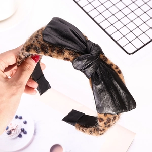 Detail of leopard print headband with a large black faux leather bow knot design