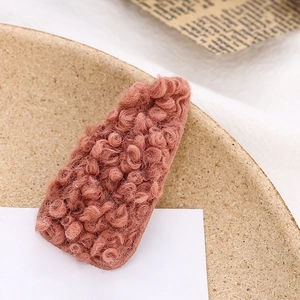 Detailed view of pinkish brown fuzzy plush faux shearling waterdrop hair clip on paper
