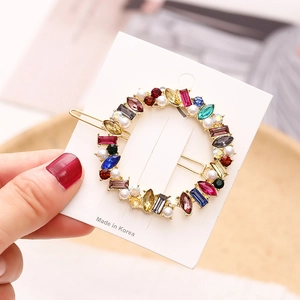 Eleganter runder Haarclip aus Goldmetall mit bunten Strasssteinen und weißen Perlen auf Karte