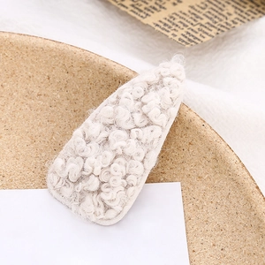 Close-up of cream lamb wool texture on waterdrop hair clip with a soft warm aesthetic