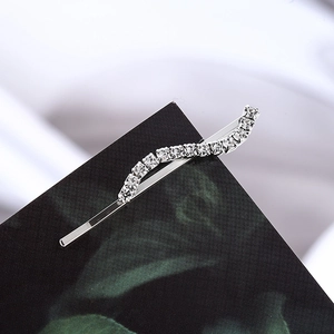 Elegant wavy silver rhinestone hair clip with sparkling crystals on a green card background