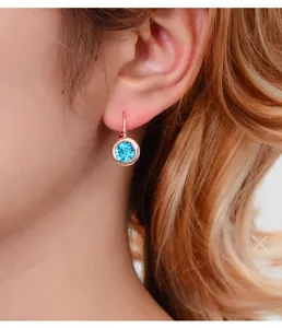 Gros plan de boucles d'oreilles en cristal bleu clair et plaqué or rose sur un mannequin