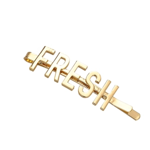 Vista dettagliata della clip per capelli dorata con la scritta FRESH in lettere maiuscole