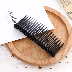 Détail d'un peigne à cheveux noir à 20 dents orné de strass sur un plateau décoratif