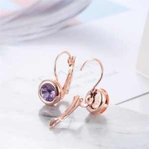 Gros plan sur des boucles d'oreilles or rose avec cristaux violets de taille ronde