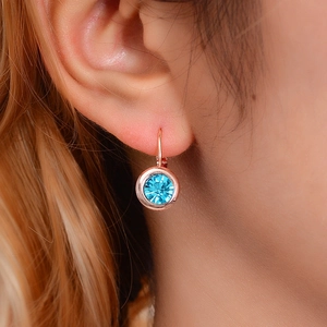Boucles d'oreilles créoles dorées roses avec cristal bleu portées sur l'oreille