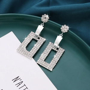 Macro detail of silver rectangular drop earrings with floral studs and sparkling crystals