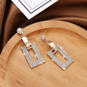 Sparkling long rectangle drop earrings with rhinestones on a warm display stand