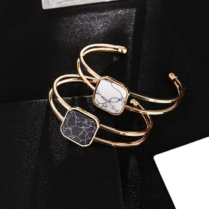Double-layer gold bangle with black and white square marble stones in a minimalist design