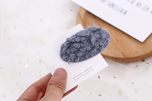 Détail d'une pince à cheveux en peluche laine d'agneau bleu gris sur carte