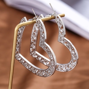 Macro detail of silver heart hoop earrings with intricate floral pattern engraving