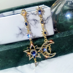 Asymmetric 925 silver star and moon earrings with blue stones on a marble box