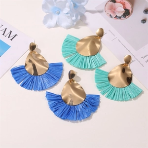 Detail of colorful fan-shaped raffia earrings with golden metal teardrop studs