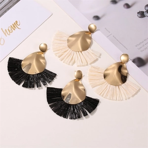 Detail showing colorful fan-shaped raffia earrings in black and beige with gold sequins