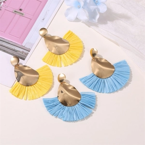 Detail of yellow and blue fan-shaped raffia tassel earrings with gold irregular metal plates