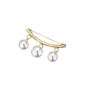 Broche élégante en métal doré avec trois perles blanches sur fond blanc épuré
