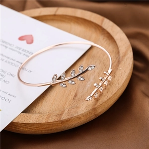 Rose gold adjustable leaf bangle set with sparkling crystals on a wooden surface