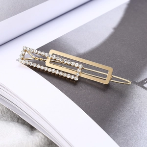 Macro detail of a golden rectangular hair clip with shimmering white rhinestones