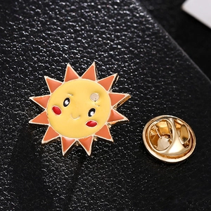 Spilla smaltata a forma di sole con viso sorridente su superficie in pelle nera lucida