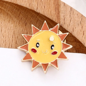 Spilla a forma di sole in smalto con viso sorridente e bordo in metallo dorato